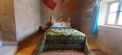 a bedroom with a bed in the corner of a room at Dar Gamra in Merzouga