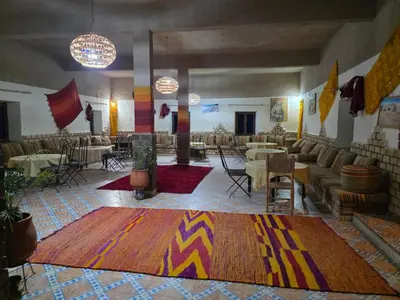 a large room with couches and tables and a rug at Dar Gamra in Merzouga