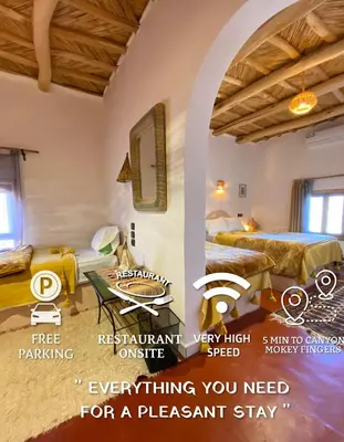 a room with two beds and a table in it at Miguirne Chez Ali in Tamellalt