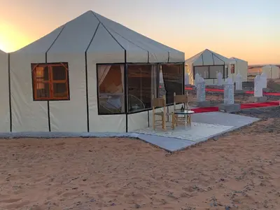 a tent in the desert with a table and chairs at Palmyra Luxury Camp in Merzouga