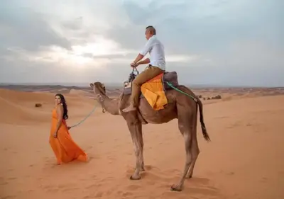 a man riding a camel in the desert with a woman at Desert Luxury Tented & Activities in Hassilabied