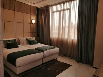 a bedroom with two beds and a large window at Hôtel Volubilis Meknès in Meknès