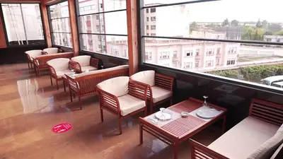 a restaurant with chairs and tables and a large window at Hôtel Volubilis Meknès in Meknès