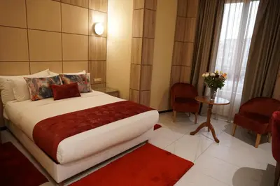 a bedroom with a large bed with a red rug at Hôtel Volubilis Meknès in Meknès