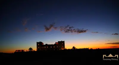 a silhouette of a building on a hill at sunset at Sunrise Palace Merzouga in Merzouga