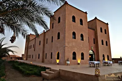 a large brick building with tables in front of it at Sunrise Palace Merzouga in Merzouga