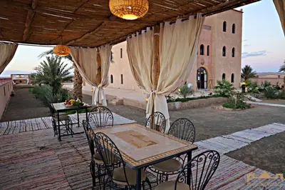 a patio with tables and chairs and a building at Sunrise Palace Merzouga in Merzouga