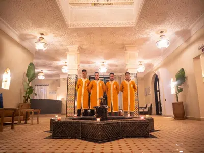four men in orange robes standing on a table in a room at Dar Morocco in Merzouga