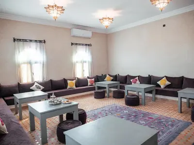 a living room with a couch and tables and windows at Dar Morocco in Merzouga