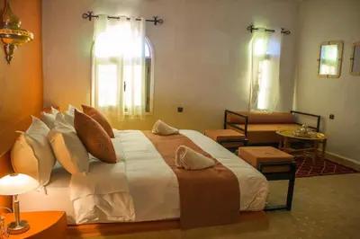a bedroom with a large bed and a living room at Dar Morocco in Merzouga