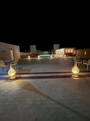 a parking lot with two benches and lights at night at Dar Morocco in Merzouga