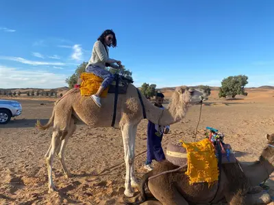 a girl riding on a camel in the desert at Merzouga Luxury Tents - Glamping in Merzouga