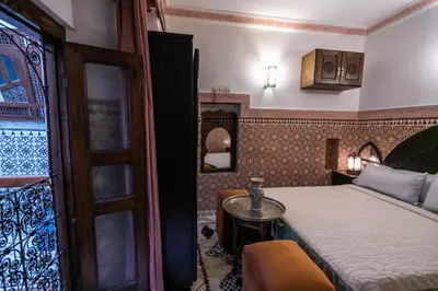 a bedroom with a bed and a table and a door at Riad Dar Barae in Fès al Bali