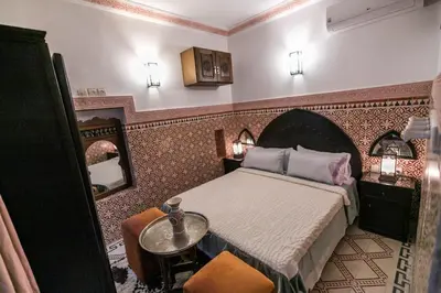 a bedroom with a bed and a table and a mirror at Riad Dar Barae in Fès al Bali