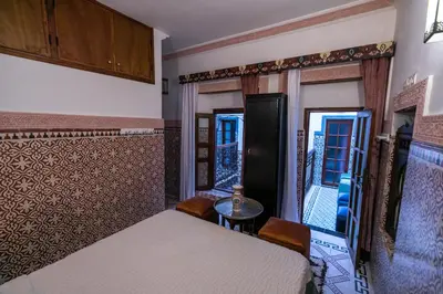 a bedroom with two beds and a table and a window at Riad Dar Barae in Fès al Bali
