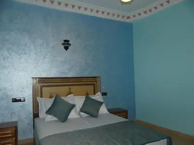 a bedroom with a bed with blue walls at Luxury Family Apartment in Merzouga