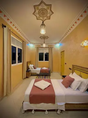 a bedroom with two beds and a chandelier at Luxury Family Apartment in Merzouga