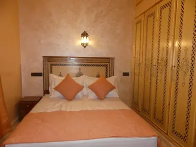 a bedroom with a bed with white sheets and orange pillows at Luxury Family Apartment in Merzouga