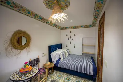 a bedroom with a bed and a mirror and a table at Riad Moroccan Style in Fès