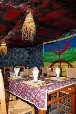 a table in a restaurant with a table cloth on it at Nomada Desert Camp in Merzouga