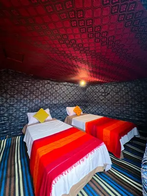 two beds in a room with a red ceiling at Nomada Desert Camp in Merzouga