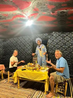 a group of people sitting around a table with a woman at Nomada Desert Camp in Merzouga