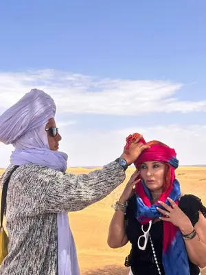 a woman is cutting another womans hair in the desert at Nomada Desert Camp in Merzouga