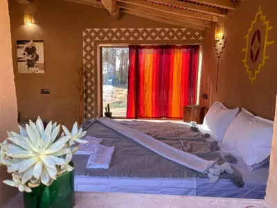 a bedroom with a large bed and a window at Camp Auberge Sahara Marokko in Mhamid
