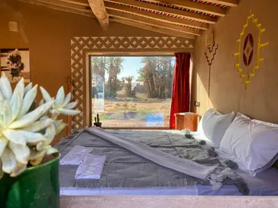 a large bed in a room with a window at Camp Auberge Sahara Marokko in Mhamid