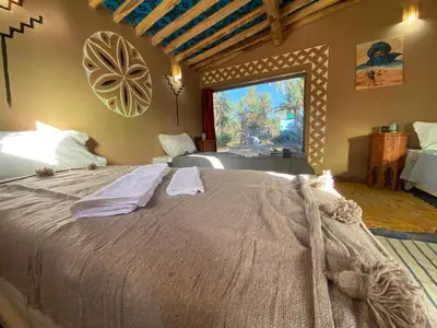 a bedroom with a large bed with a large window at Camp Auberge Sahara Marokko in Mhamid