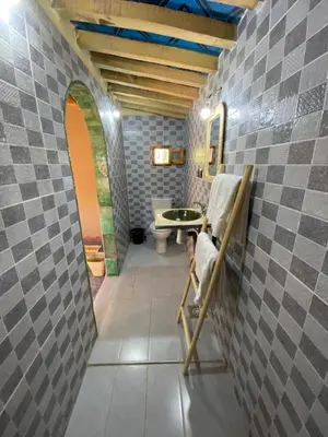 a bathroom with a toilet and a chair on a tiled wall at Camp Auberge Sahara Marokko in Mhamid