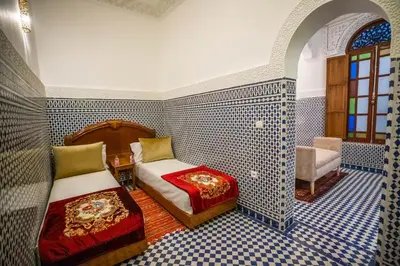 a bedroom with two beds in a room with blue tiles at Riad Dilar Fes & Spa in Fès