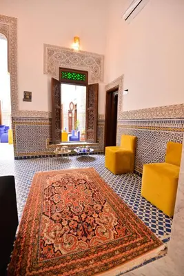 a room with a rug and two yellow chairs and a mirror at Riad Dilar Fes & Spa in Fès