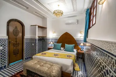 a bedroom with a bed in a room with blue and white tiles at Riad Dilar Fes & Spa in Fès
