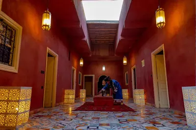 a person standing in a red room with a suitcase at Dar Oussidi in Merzouga