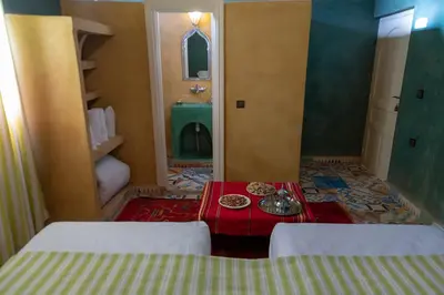 a room with two beds and a table with plates on it at Dar Oussidi in Merzouga