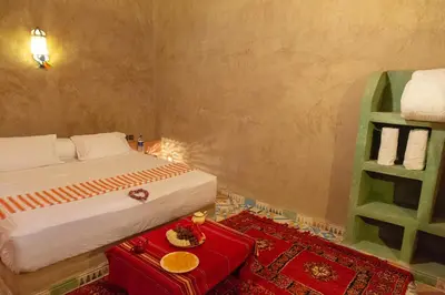 a bedroom with a bed and a red table at Dar Oussidi in Merzouga