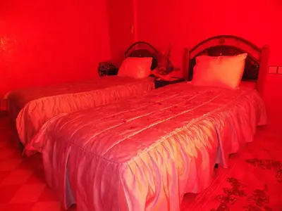 two beds in a room with red walls at Jad Auberge in Ourika