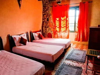 a bedroom with two beds and a window with red curtains at Jad Auberge in Ourika