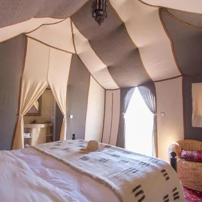 a bedroom with a bed with a comforter on it at Merzouga Horizon Luxury Camp in Merzouga