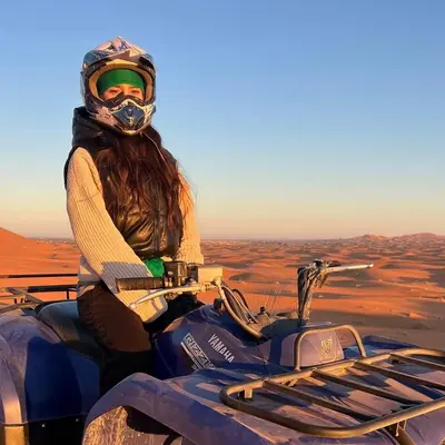a woman riding a motorcycle in the desert at Merzouga Horizon Luxury Camp in Merzouga