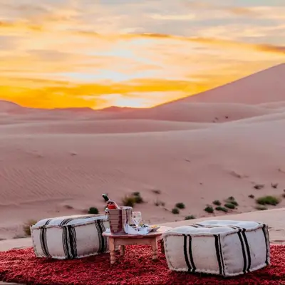 a table and chairs in the desert at sunset at Merzouga Horizon Luxury Camp in Merzouga