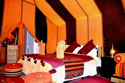 a bedroom with a bed with an orange canopy at Authentique merzouga camp in Merzouga