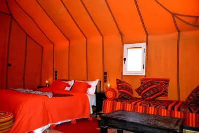 an orange room with two beds and a window at Authentique merzouga camp in Merzouga