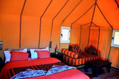 an orange room with two beds and a chair at Authentique merzouga camp in Merzouga