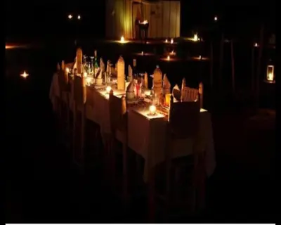 a long table with white tables and chairs at night at Authentique merzouga camp in Merzouga