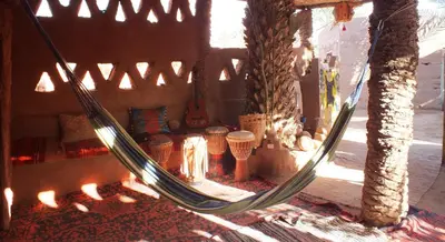 a hammock in a room with a fireplace at Auberge Tigida in Mhamid