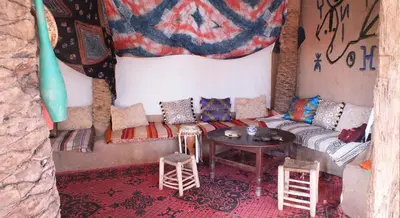 a room with a couch and a table and stools at Auberge Tigida in Mhamid