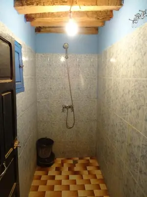 a bathroom with a shower with a tile floor at Auberge Tigida in Mhamid