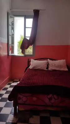 a bedroom with a bed with a red wall and a window at Hôtel Glacier in Fès